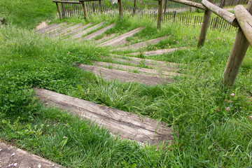 Fototapeta na wymiar Wooden spiral down steps of old stairs on the nature and green grass life path walk way concept