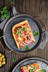 Homemade healthy Shiitake mushroom pizza topped with slices with green olives, cheese, red onion and oregano