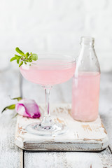 Summer refreshment drinks. Light pink rose cocktail, with rose wine on a white table. With rose flowers. Copy space
