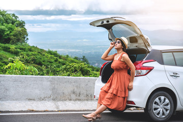 Happy and relaxation time in holiday, Young woman traveler sitting on back car and looking at beautiful mountain view with nature, Traveler car concept