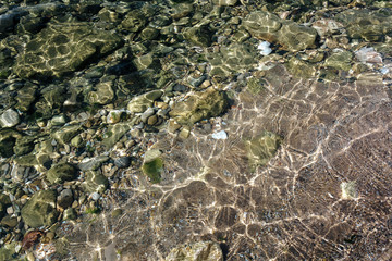 A lot of wet small stones with sand on the beach.