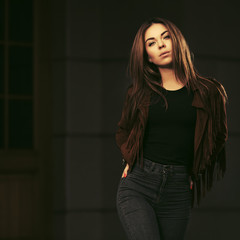 Young fashion woman in leather fringe suede jacket and dark blue jeans