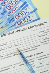 The signing of a bilateral agreement of renting a car from an individual. Russian rubles, a pen and the text "car rental Agreement" on the table