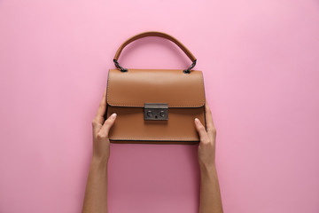 Woman holding stylish handbag on pink background, closeup
