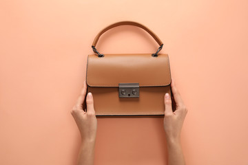 Woman holding stylish handbag on beige background, closeup