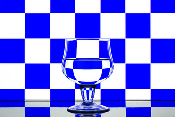 Glass on a blue and white background with a reflection on the table.