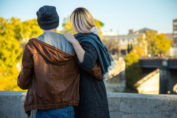 Young couple walking in the city of Rome alone.  Tiberina island in background. Casual style