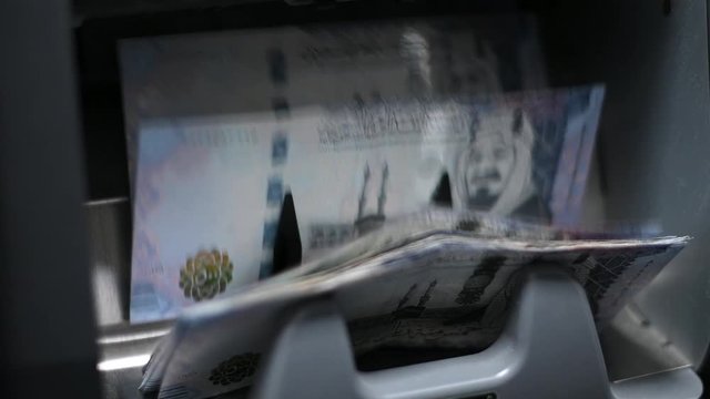 Currency counting machine counting Saudi Riyal 500 banknotes. Banking and commercial activity. Bank automatic equipment for counting paper money. Close up cash money counting equipment