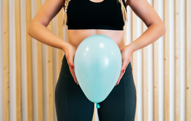 Close up of a young woman holding a balloon to explain the diaphragm zones, core and pelvic floor. Pelvic floor exercises explained - 348325453