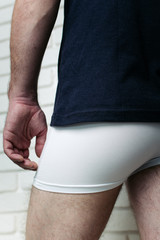 young guy in underwear: white boxers. body parts: elastic male buttocks and hairy legs of a young...