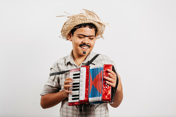 Brazilian boy wearing typical clothes for the Festa Junina - June festival - playing toy accordion