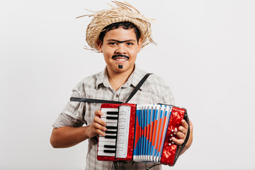 Brazilian boy wearing typical clothes for the Festa Junina - June festival - playing toy accordion