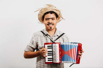 Brazilian boy wearing typical clothes for the Festa Junina - June festival - playing toy accordion