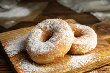Delicious donuts with powdered sugar on wooden table