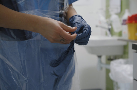 Nurse putting on latex gloves in infection room for coronavirus protection