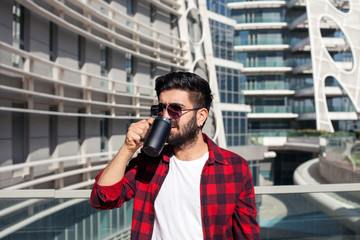 Businessman drinking coffee and thinking about his future. Man drinking an hot coffee with a cup in front of the modern building.
