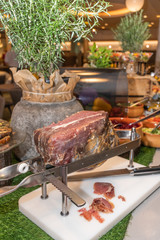 Jamon serrano spanish raw smoked ham in a slicing machine, during brunch buffet