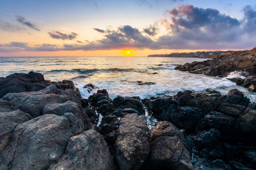 Fototapeta na wymiar coast of the ocean at sunset. beautiful landscape with rocks in the water. gorgeous cloudscape above the sun and horizon. concept of calmness and mediatation