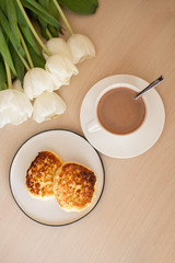 view above of cup with cacao and saucer on the table, white tulips; morning Breakfast with cacao (vertically)
