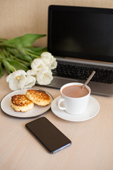 cacao and homemade cheesecakes on a plate, breakfast on a freelance, phone, laptop on the table (vertically)