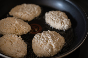 homemade cheesecakes are fried in a frying pan, the process of cooking homemade cheesecakes (close up)