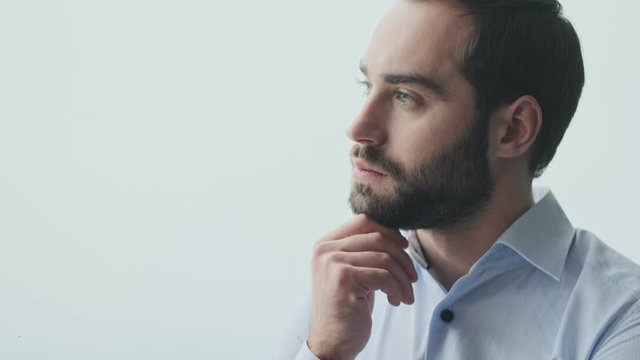 Handsome concentrated young business man indoors in office thinking