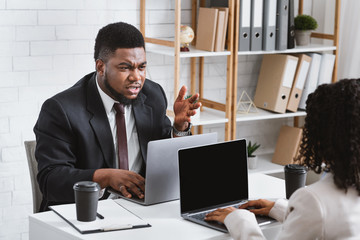 Young African American coworkers having argument at workplace, blank space