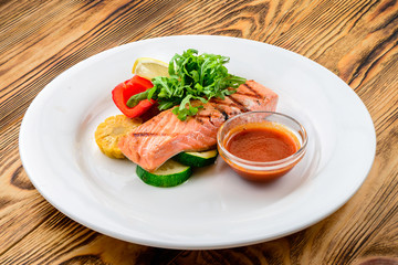 salmon with salad and vegetables - dish on a wooden background