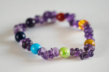 Semiprecious stone balls on a leash with amethysts on a hand on a white background.