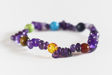 Semiprecious stone balls on a leash with amethysts on a hand on a white background.