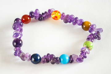 Semiprecious stone balls on a leash with amethysts on a hand on a white background.