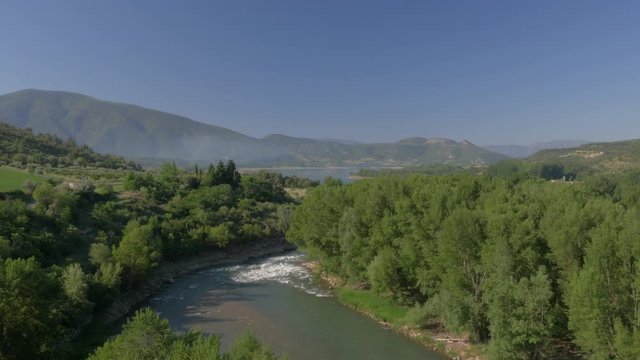 AERIAL DRONE SHOT OF RIVER IN GREEN VALLEY AND RESERVOIR IN BACKGROUND