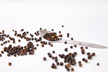 organic black pepper and metal spoon