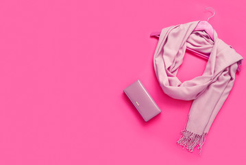 Beautiful pink woolen scarf and beautiful leather wallet on paper background.
