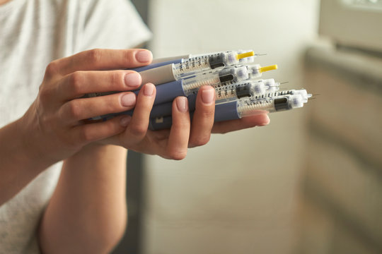 Diabetes insulin dependent concept, hands with syringes pen injectors with doses of humalog for subcutaneous abdomen injection therapy