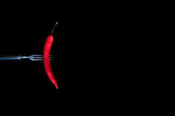 Vintage fork with red chili pepper on black background, selective focus