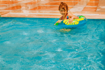 Cute child girl having fun with water in the swimming pool. Summer holiday, adventure and happy childhood concept. Horizontal image.
