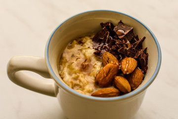Oat porridge in cup for breakfast, on light colored table. Healthy eating, healthy food for breakfast