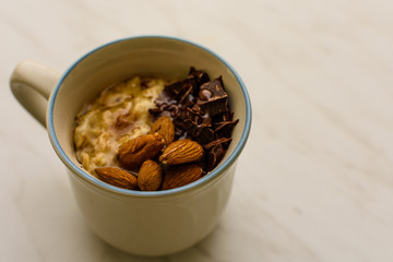 Oat porridge in cup for breakfast, on light colored table. Healthy eating, healthy food for breakfast