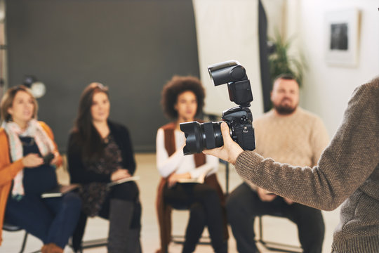 Lecturer showing to his attendees parts of camera.