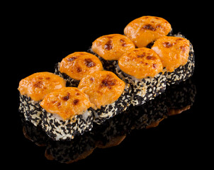 Hot Sushi roll with salmon, sesame and sauce on top isolated on black background with reflection