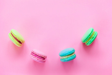 Sweet almond colorful pink blue yellow green macaron or macaroon dessert cake isolated on trendy pink pastel background. French sweet cookie. Minimal food bakery concept. Flat lay top view, copy space