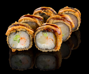 Hot Fried Uramaki Sushi roll with shrimp, scallop, cheese, cucumber, avocado and sauce isolated on black background with reflection