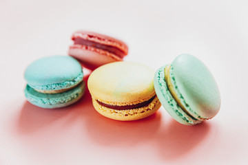 Sweet almond colorful pink blue yellow green macaron or macaroon dessert cake isolated on trendy pink pastel background. French sweet cookie. Minimal food bakery concept. Flat lay top view, copy space