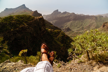 Legs of traveler sitting on a high mountain top in travel. Freedom concept. Tenerife