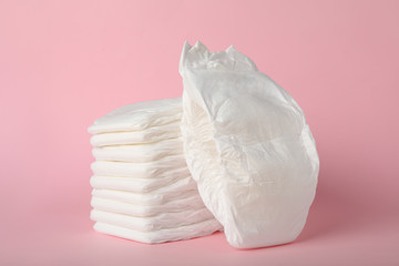 Stack of baby diapers on pink background