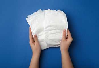 Woman with diapers on blue background, closeup
