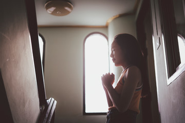 Fototapeta na wymiar Portrait of Asian beautiful young woman while praying worship for christian religion in the window, Christian Religion concept.