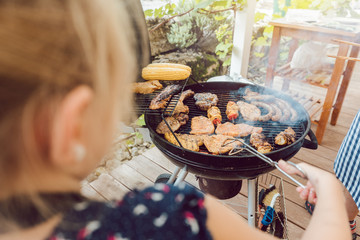 Little girl grilling the meat for the BBQ