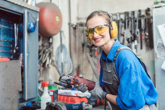 Woman mechanic working with disk grinder